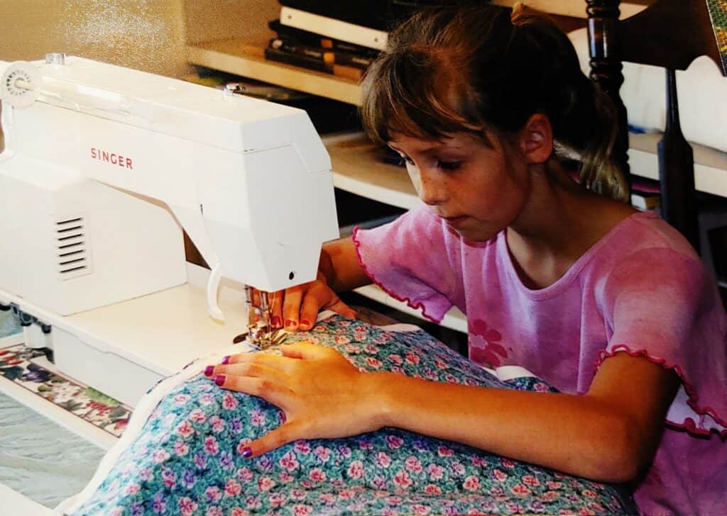 A little girl sews on a sewing machine